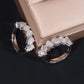 Pair of diamond earrings on a dark surface with a beige jewelry box in the background.