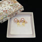 Dior earrings with pink pearls and gold stars in a Dior box on a black background