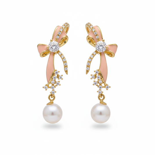 Pair of earrings with pink bows, gold accents, and pearl drops on a white background