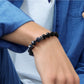 Person wearing a black beaded bracelet on a white background