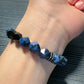 Blue beaded bracelet on a wrist with a gray textured background