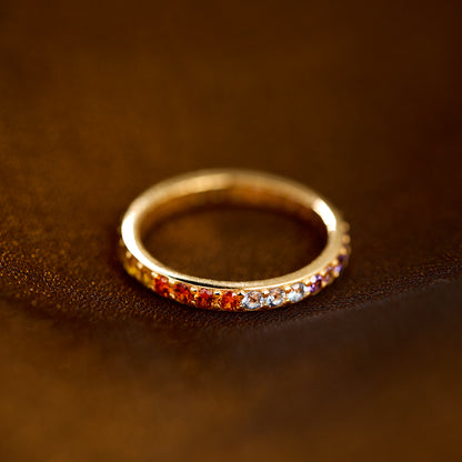 Gold ring with colorful stones on a brown leather surface