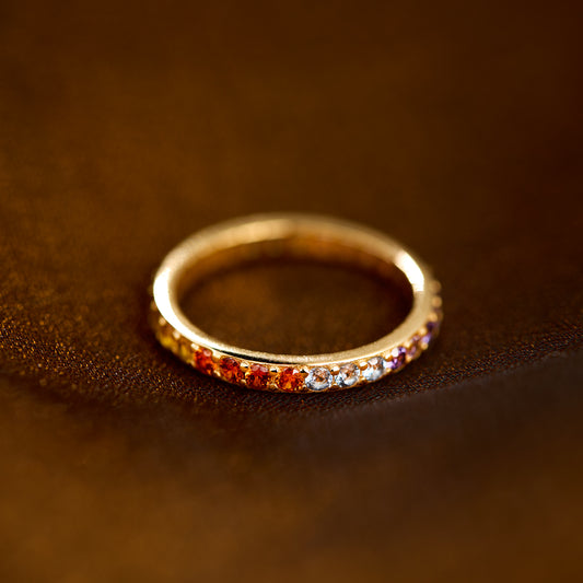 Gold ring with colorful stones on a brown leather surface