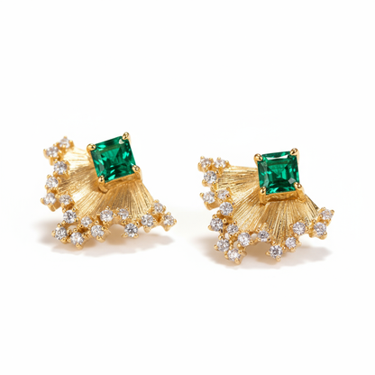 Gold earrings with green gemstones on a white background