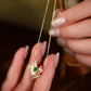 Gold necklace with a green gemstone held by a hand against a blurred background
