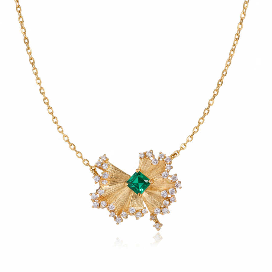 Gold necklace with a green gemstone pendant on a white background