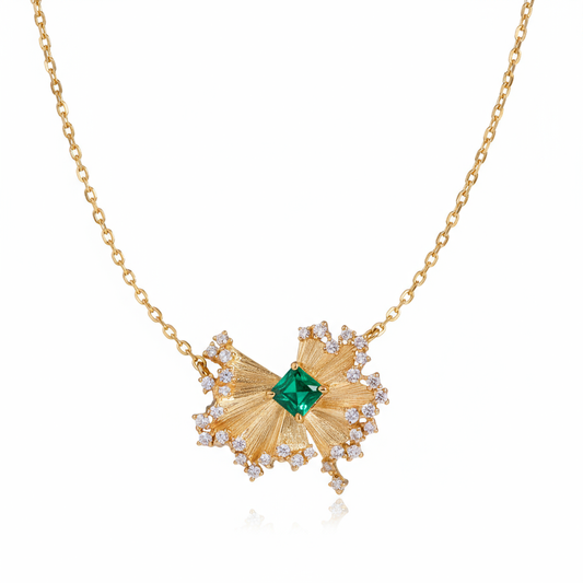Gold necklace with a green gemstone pendant on a white background