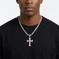 Man wearing a black shirt with a silver cross necklace against a white background