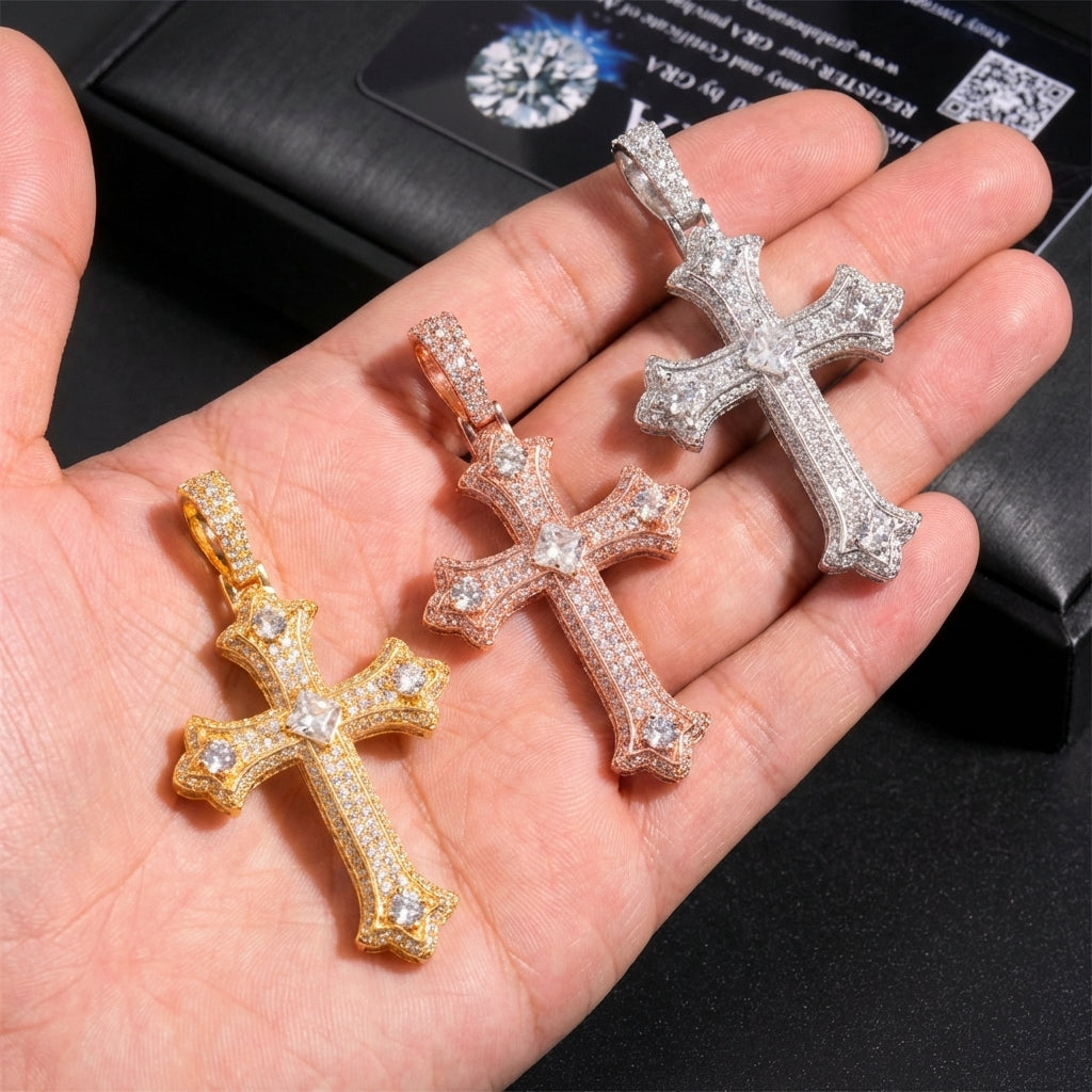 Three cross-shaped pendants in gold, rose gold, and silver held in a hand with a black background.