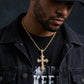 Man wearing a gold cross necklace with a dark background