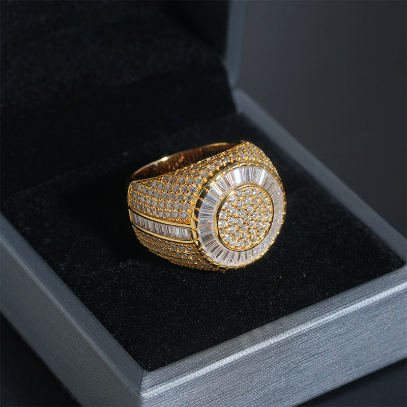 A gold signet ring with pave-set clear stones, displayed inside a black velvet-lined jewelry box.