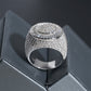 A silver-toned statement ring with a wide, heavily embellished pavé band and a circular textured top, displayed on a dark gray geometric surface.