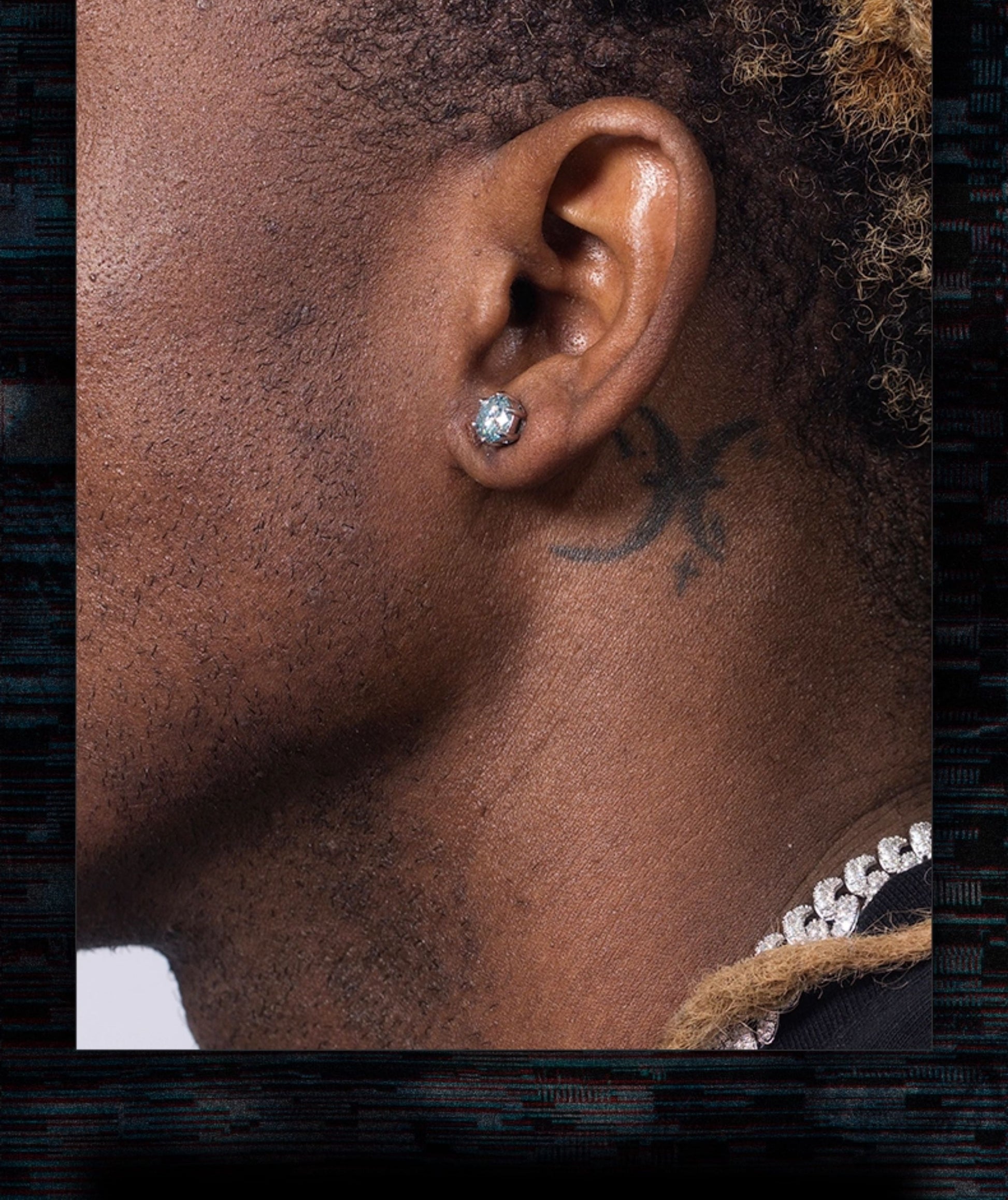 Close-up of an ear with a diamond earring and a tattoo on the neck.