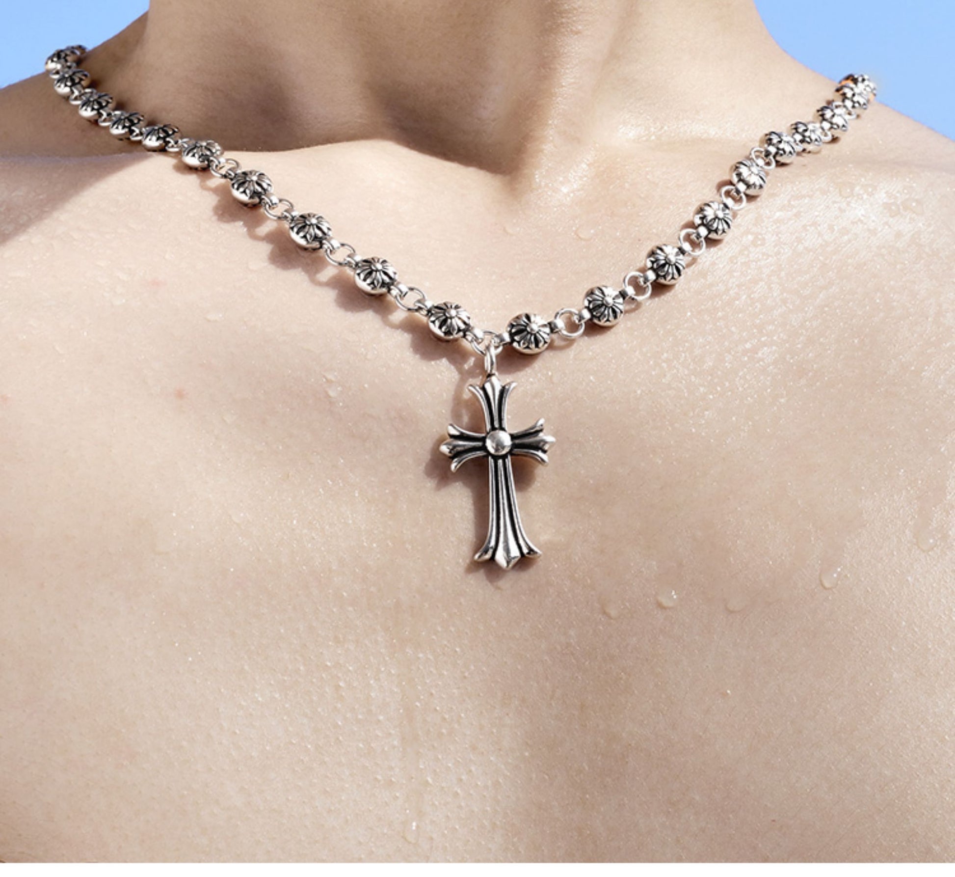 “Male model wearing punk-inspired beaded silver cross necklace”