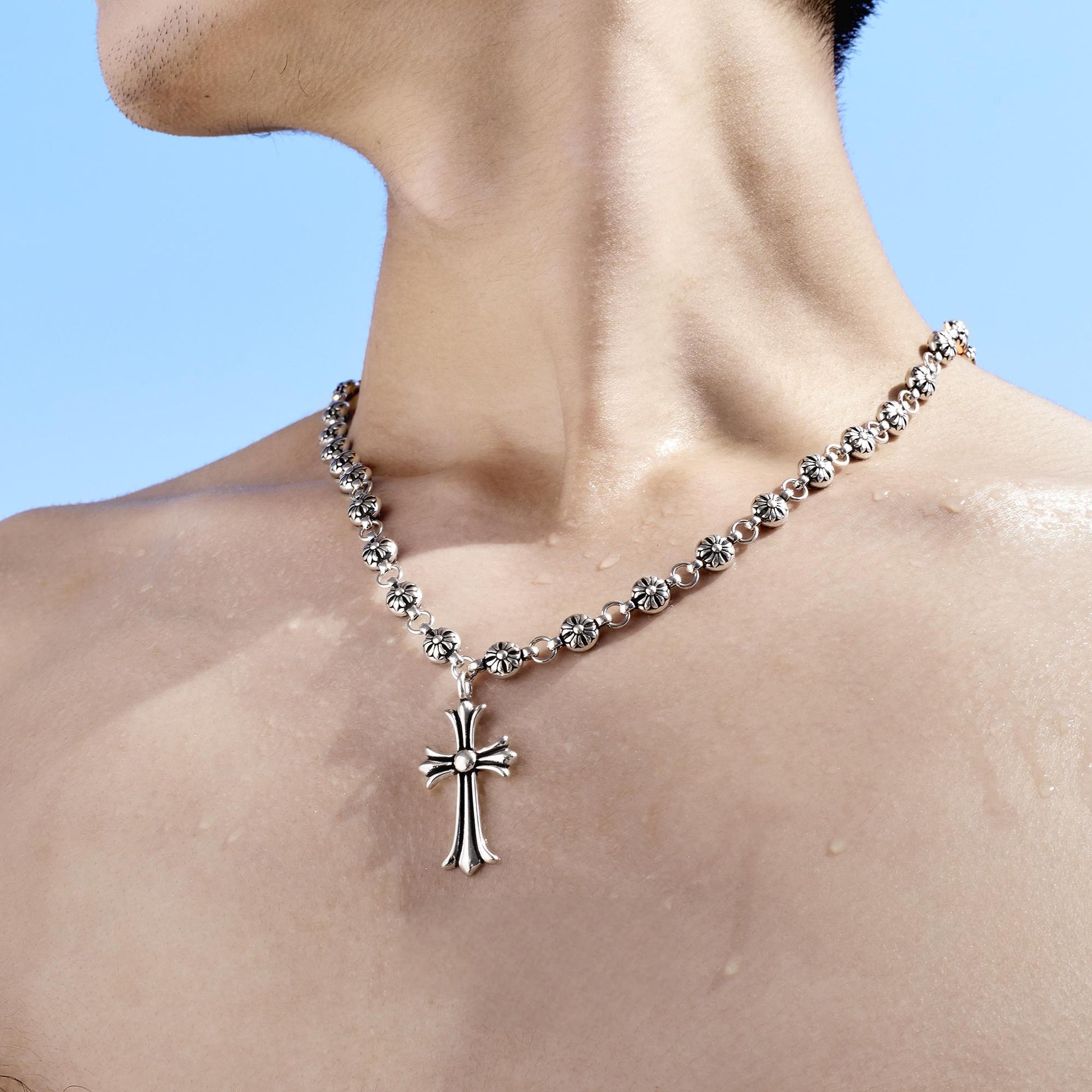 “Streetwear styling with sculptural cross pendant layered with chains”