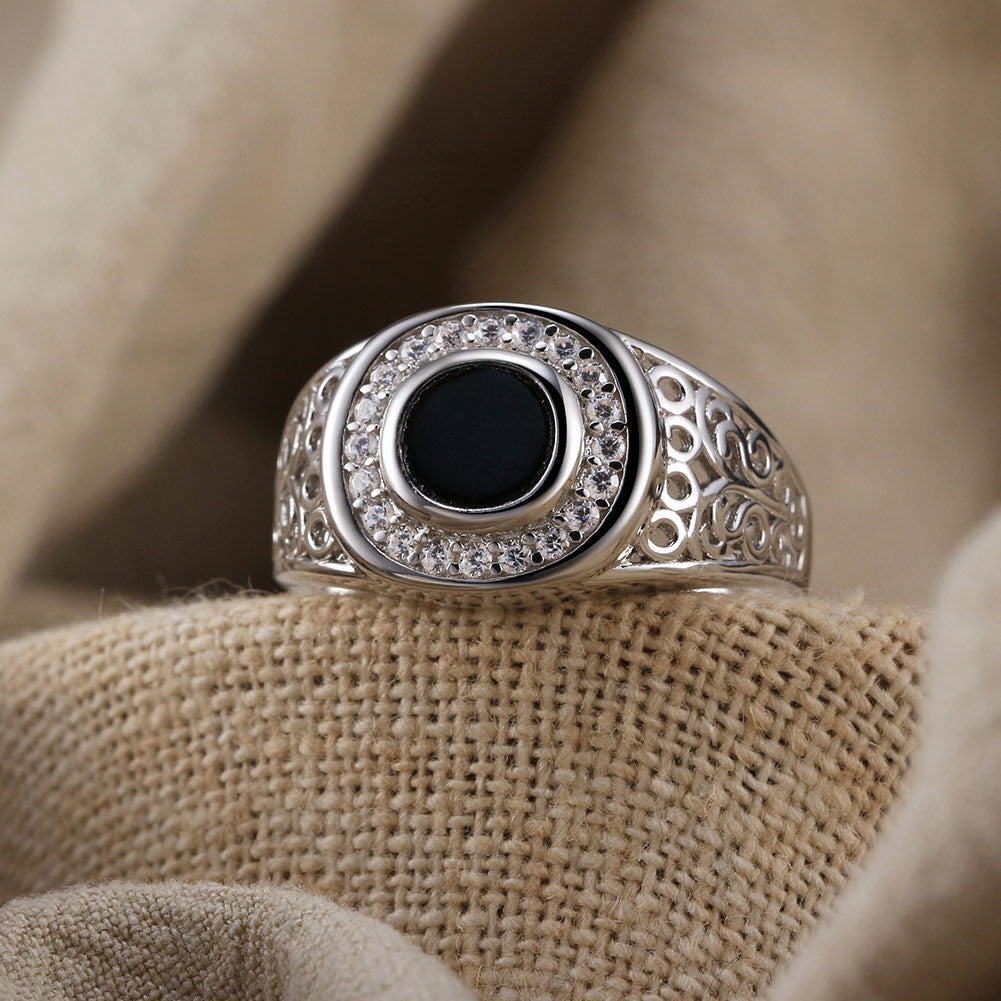 “Close-up of handcrafted S925 sterling silver Turkish ring with black onyx gemstone”Silver ring with black center stone on beige fabric