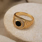 “Close-up of handcrafted S925 sterling silver Turkish ring with black onyx gemstone”Gold ring with a black gemstone and diamond accents on a beige fabric background