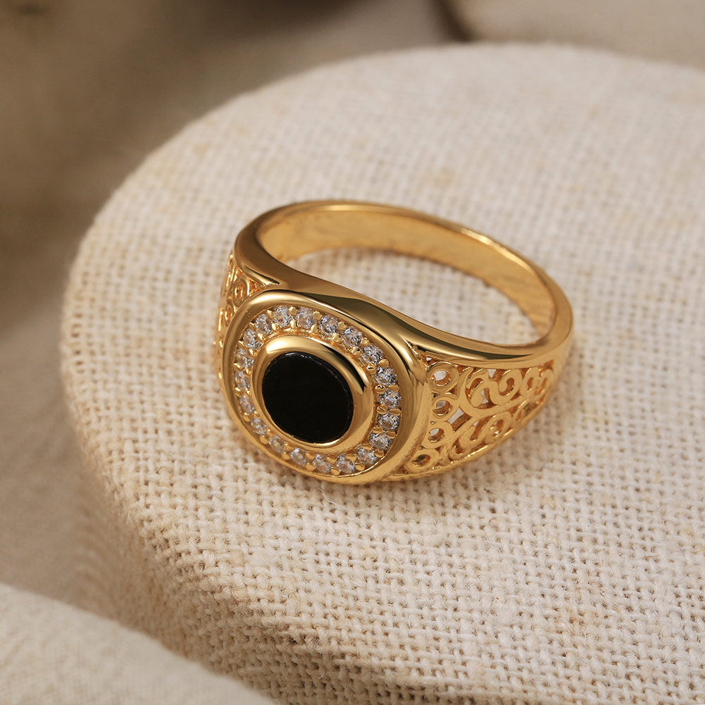 “Close-up of handcrafted S925 sterling silver Turkish ring with black onyx gemstone”Gold ring with a black gemstone and diamond accents on a beige fabric background