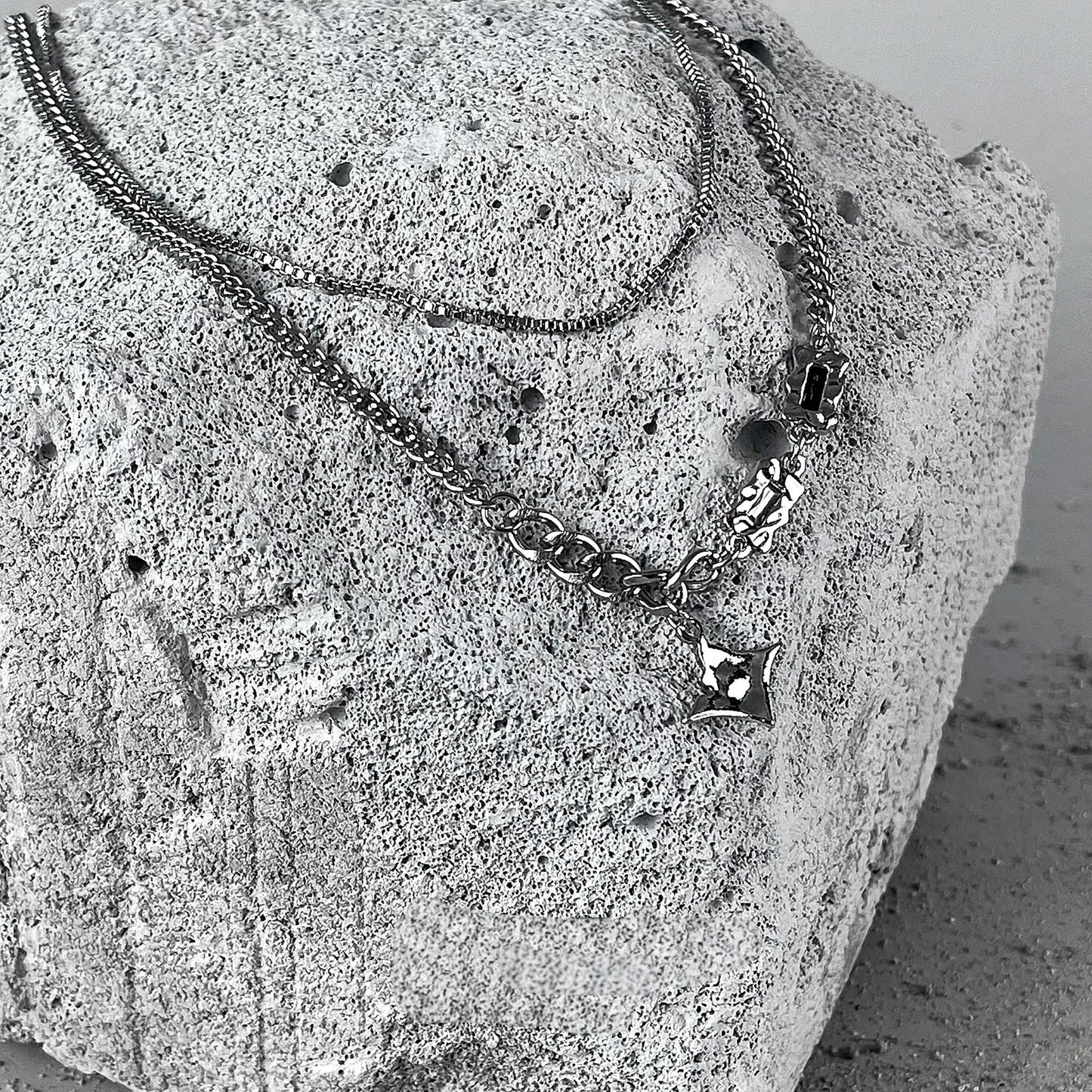 "Four-point star pendant on stacked sterling silver chain detail shot"