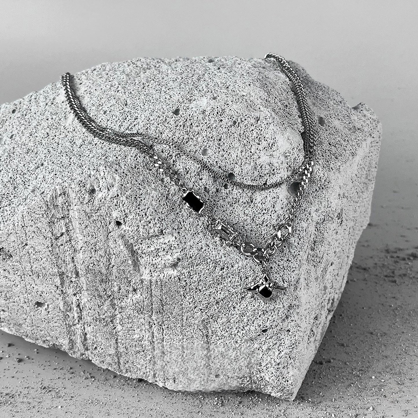 "Four-point star pendant on stacked sterling silver chain detail shot"