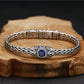 Silver bracelet with a blue gemstone on a wooden block against a dark background