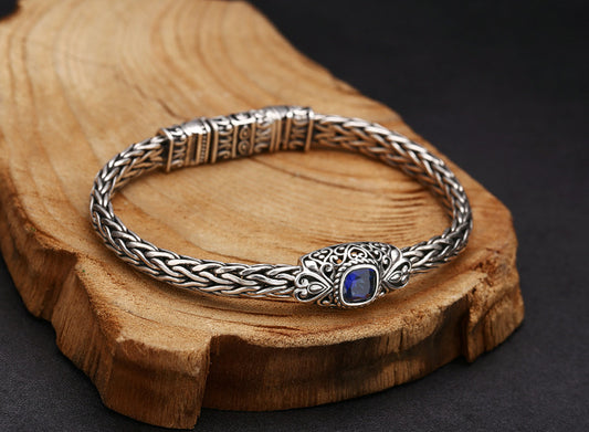 Silver bracelet with a blue gemstone on a wooden surface
