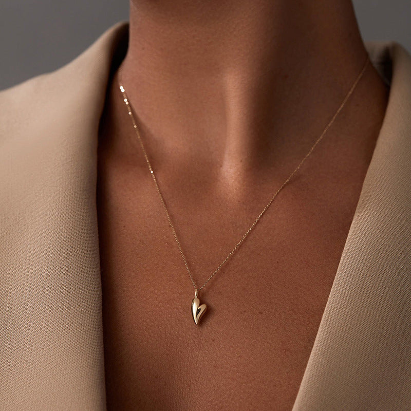 “Female model wearing minimalist heart necklace in silver”