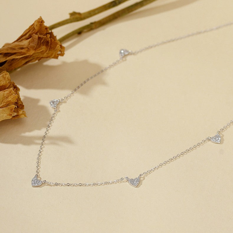 “Close-up of dainty cubic zirconia heart pendant in polished silver finish”