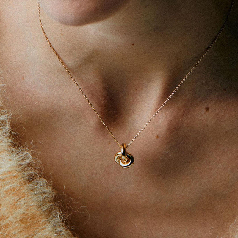 “Woman wearing minimalist silver interlocking rings necklace with elegant neckline”