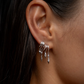 Close-up of an ear wearing silver S925 Sterling Silver Lynx Stacked Triple Hoop Huggie Illusion Earringshoop earrings with a blurred background