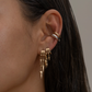 Close-up of an ear with gold S925 Sterling Silver Lynx Stacked Triple Hoop Huggie Illusion Earringsand a ring, against a neutral background