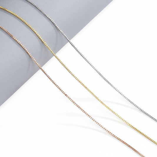 “S925 sterling silver mixed link necklace flat lay with box and bead chain details”Three gold chains of different thicknesses on a white and gray background