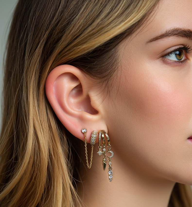 Close-up of a woman's ear wearing multiple gold earrings with gemstones.S925 Sterling Silver Nyx Stars & Moon Earrings