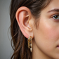 Close-up of a woman's ear wearing gold hoop S925 Sterling Silver Palma Charm Earring with dangling charms.