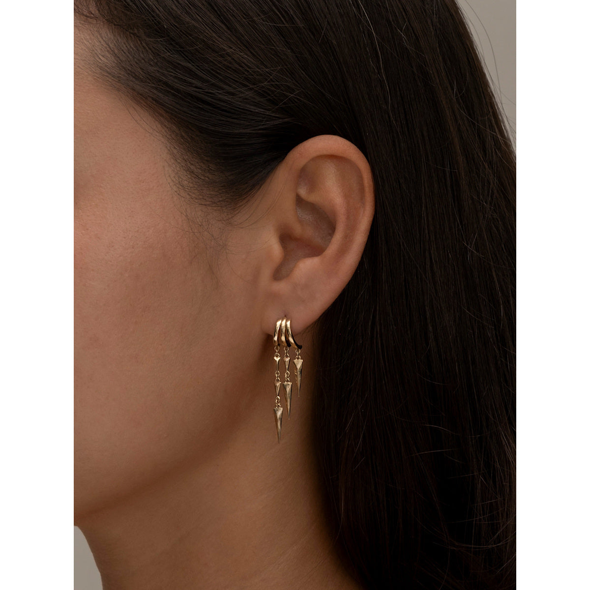 S925 Sterling Silver Paloma Illusion EarringsGold earring worn by a person with dark hair and skin.