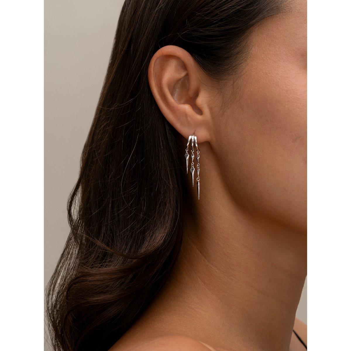 Close-up of an ear wearing a silver S925 Sterling Silver Paloma Illusion Earringswith a neutral background