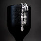 S925 Sterling Silver Petra Stacked Illusion EarringsSilver earrings on a black stand against a dark background