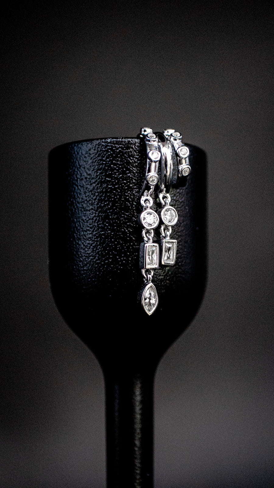 S925 Sterling Silver Petra Stacked Illusion EarringsSilver earrings on a black stand against a dark background