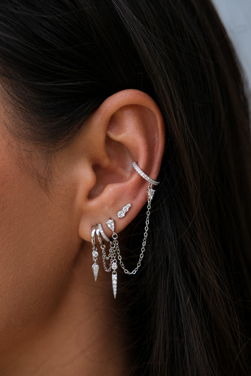 Close-up of an ear with multiple S925 Sterling Silver Petra Stacked Illusion Earringsearrings against a blurred background