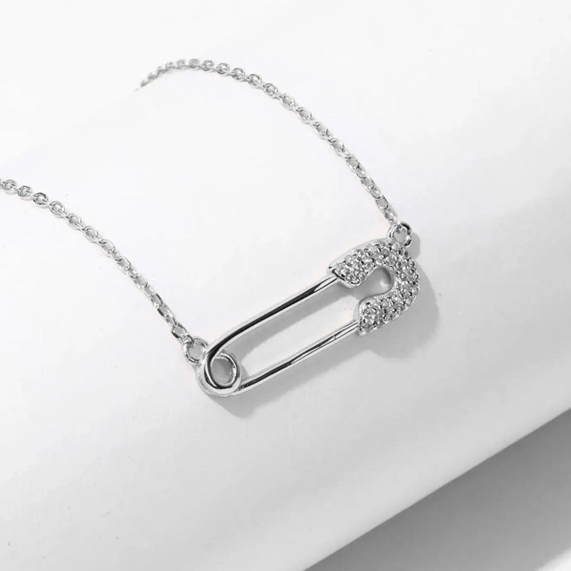 “Close-up of micro-pavé zircon safety pin pendant in polished silver finish”