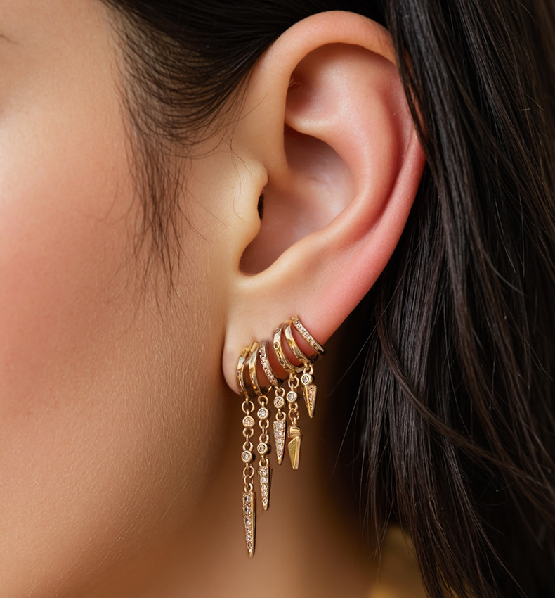 S925 Sterling Silver Sienna EarringsClose-up of an ear wearing multiple gold earrings with dangling charms.