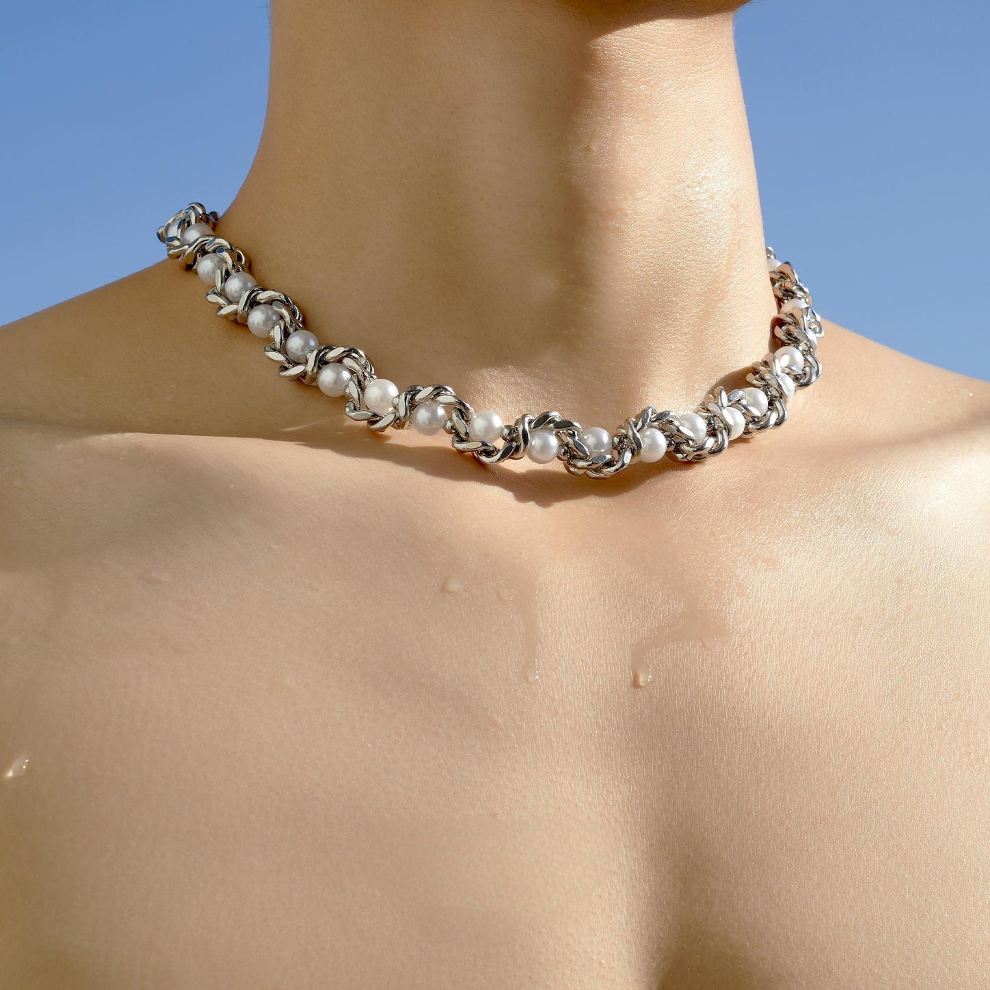 close-up of serpent-style silver choker texture and layered chain contrast”