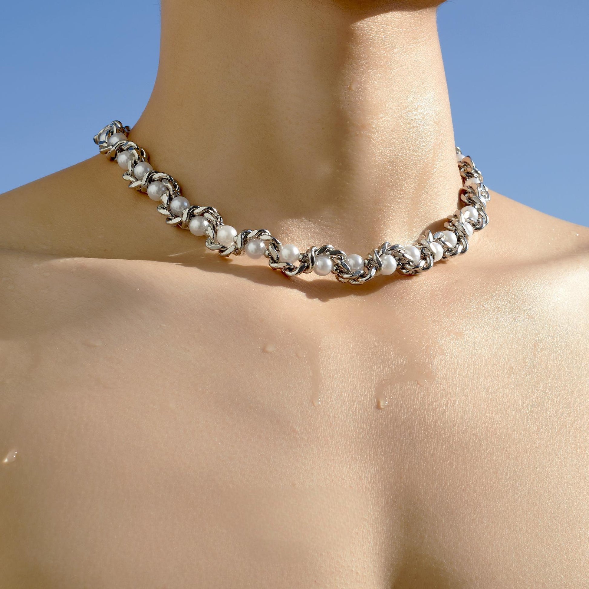 close-up of serpent-style silver choker texture and layered chain contrast”