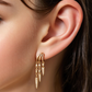 Close-up of a person wearing gold S925 Sterling Silver Spike Stud Earrings with dangling elements.