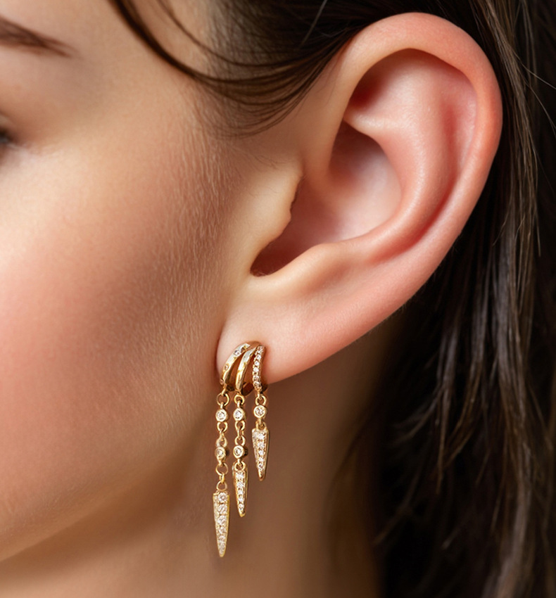 Close-up of a person wearing gold S925 Sterling Silver Spike Stud Earrings with dangling elements.