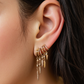 Close-up of an ear wearing multiple gold S925 Sterling Silver Spike Stud Earrings with dangling charms.