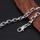 Silver chain necklace on a dark surface with a wooden piece