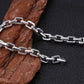 Silver chain bracelet on a textured brown rock against a black background