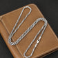 Silver chain necklace on a brown leather surface