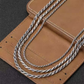 Two silver necklaces on a brown leather surface
